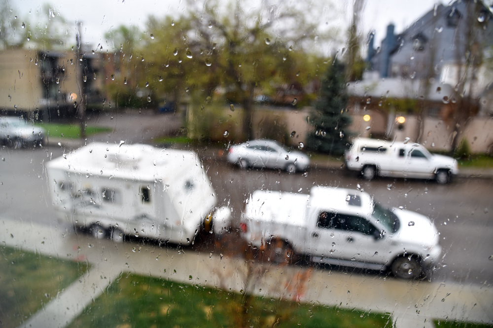 A travel trailer sits outside of a window in the rain. This RV owner completed RV hurricane prep to prepare.